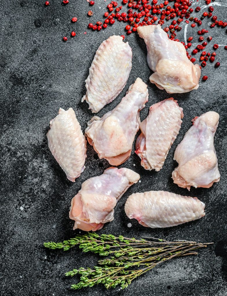 Raw chicken wings, organic poultry meat. Black background. Top view. Copy space