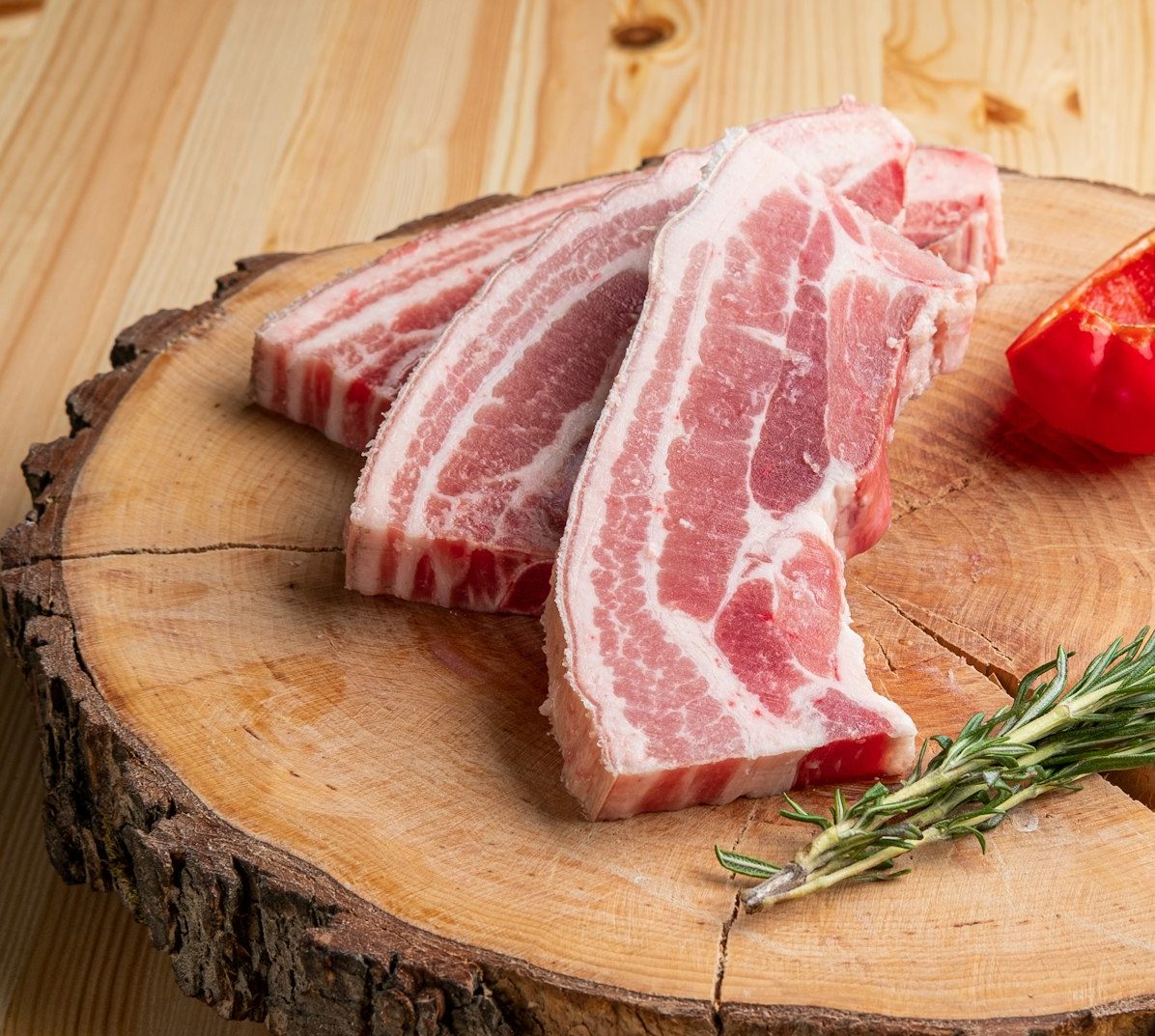 Raw fresh pork brisket slices on wooden cutting board