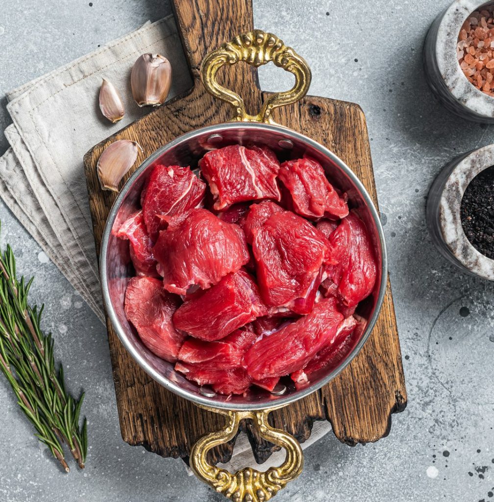 Uncooked Raw diced beef veal meat for stew in skillet. Gray background. Top view