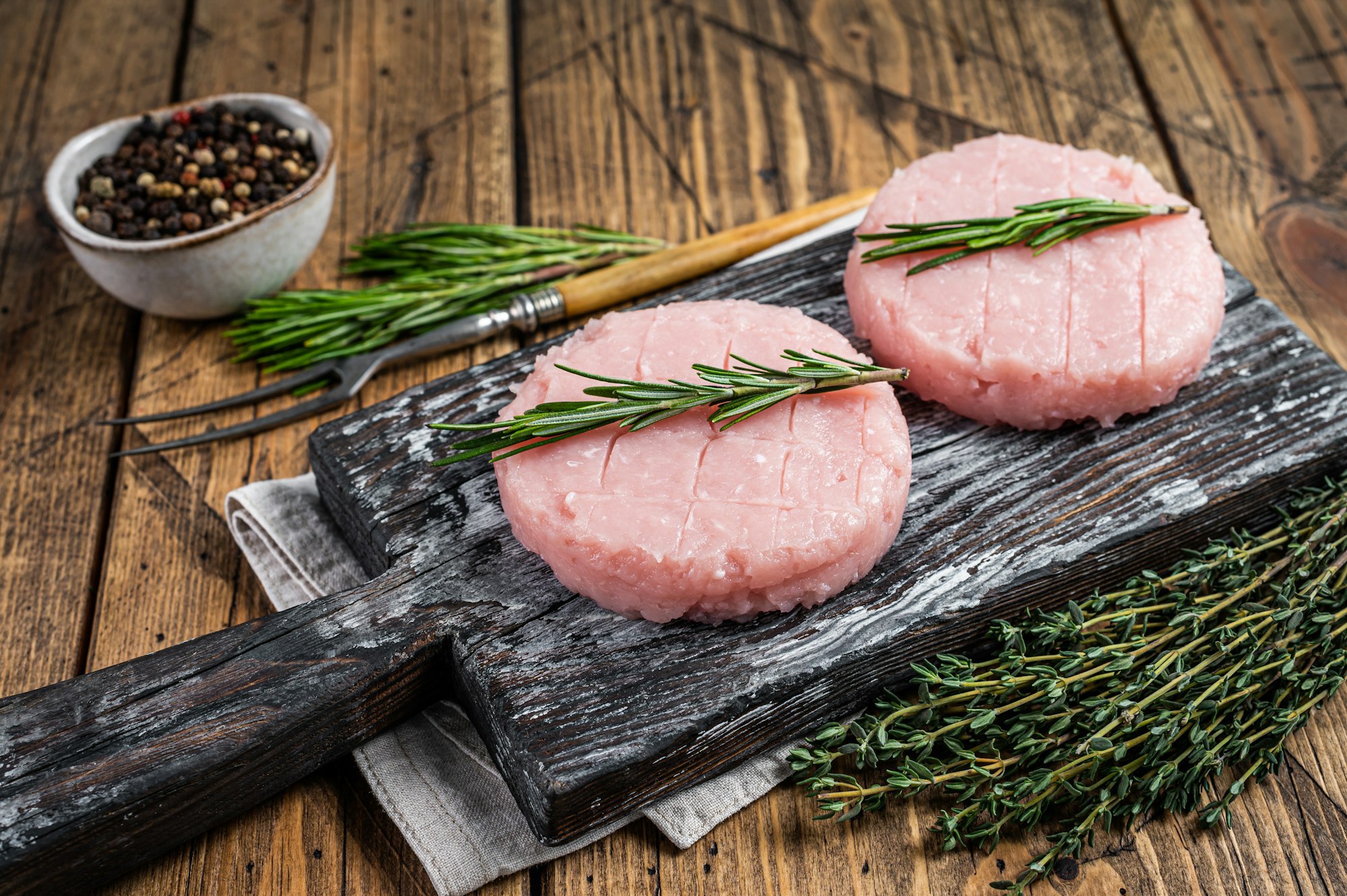 Raw burgers patty from organic chicken and turkey meat with thyme and rosemary.