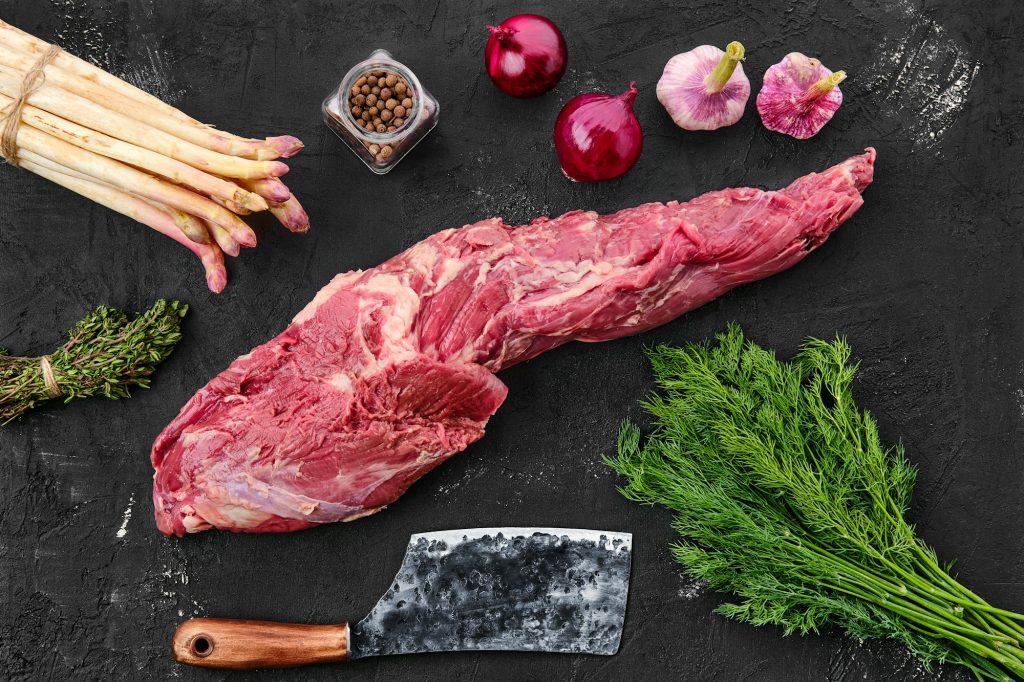 Raw fresh beef whole tenderloin with spice on black background