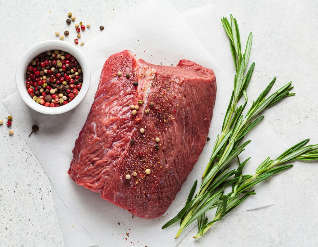 Whole piece of raw beef on gray background, top view, copy space.